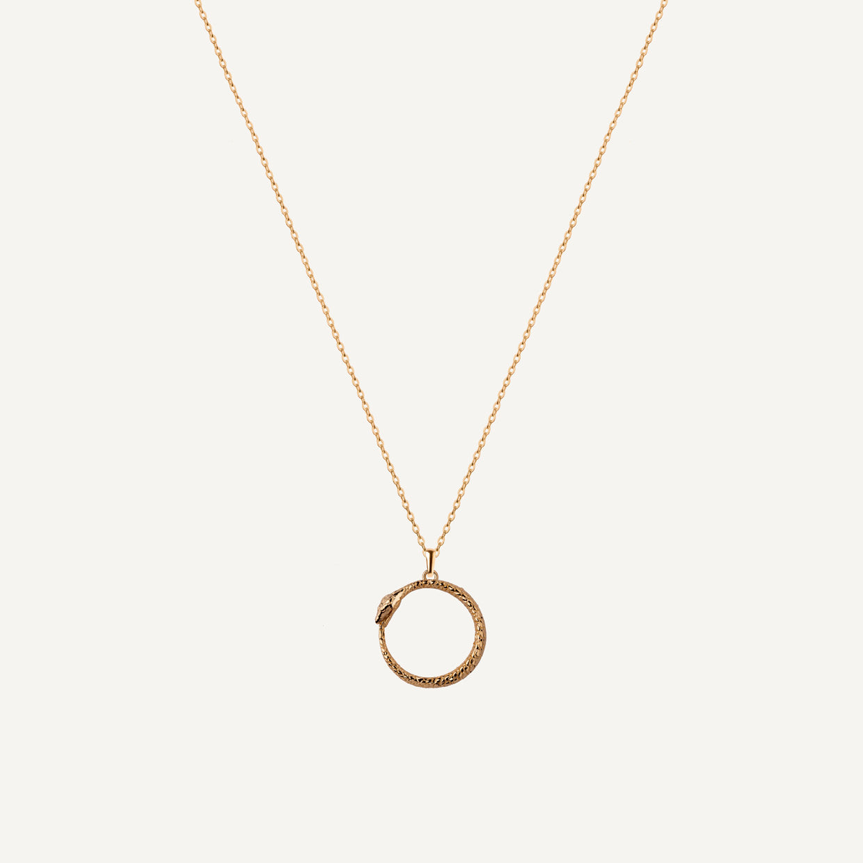 Collar Uroboros Gold es una pieza realizada a mano con métodos de joyería tradicional en latón, chapada en oro de 24k con una capa protectora que extiende la durabilidad del chapado.