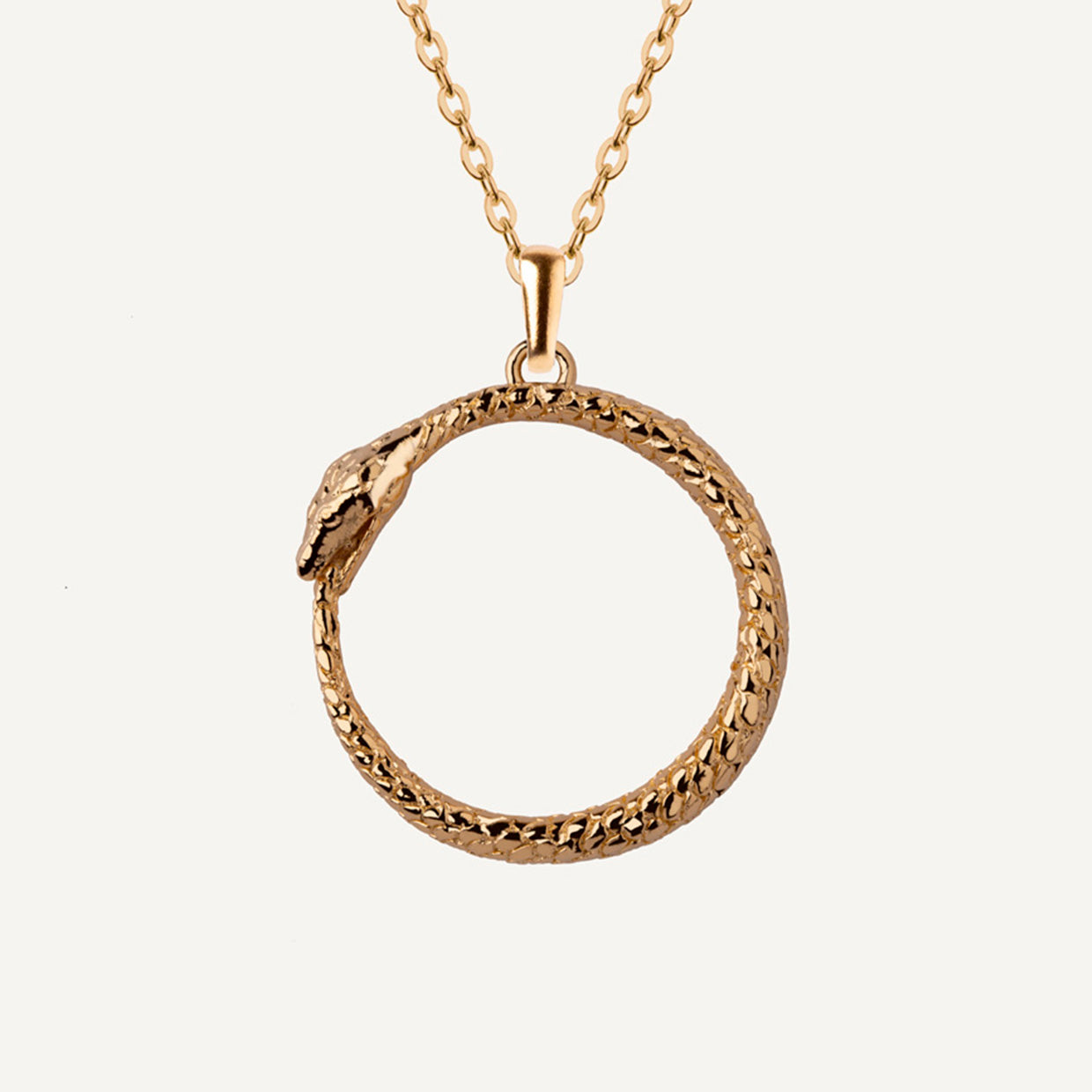 Collar Uroboros Gold es una pieza realizada a mano con métodos de joyería tradicional en latón, chapada en oro de 24k con una capa protectora que extiende la durabilidad del chapado.